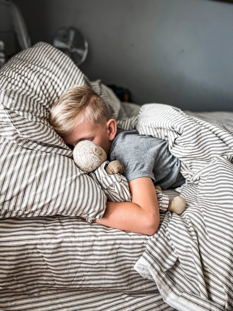 waldorf doll and a boy in stripped sheets