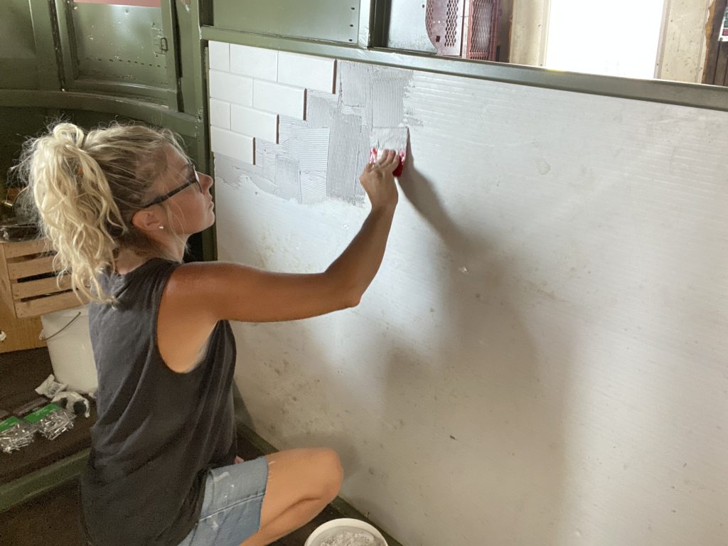 setting white subway tile in the trailer