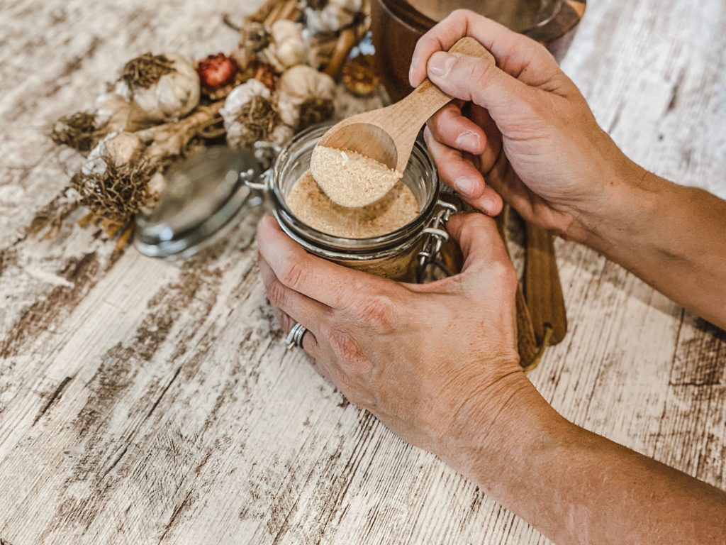 scooping garlic powder out of a glass jar