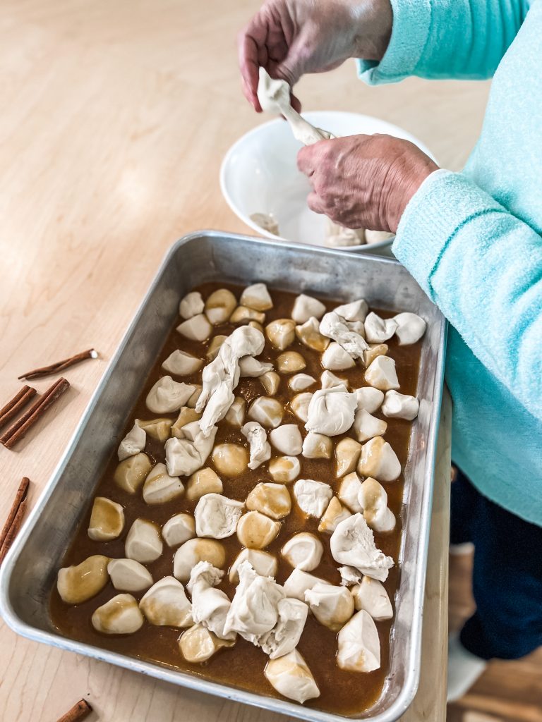 pouring the topping over frozen rolls