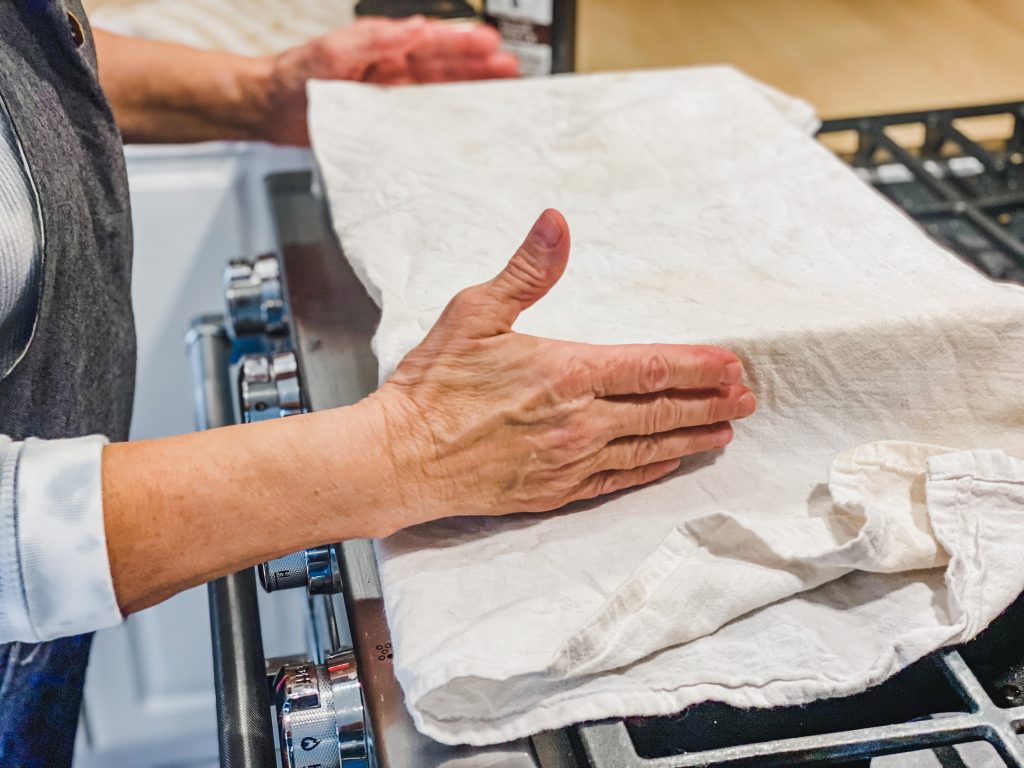 holding a covered pan with towel