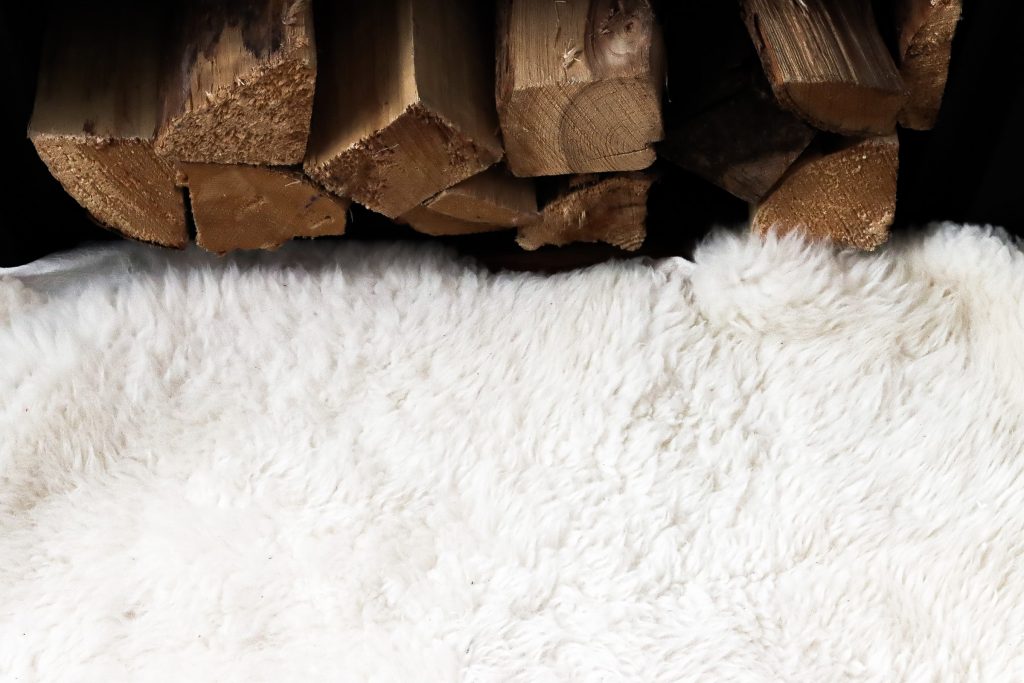 sheep rug next to a pile of cut wood