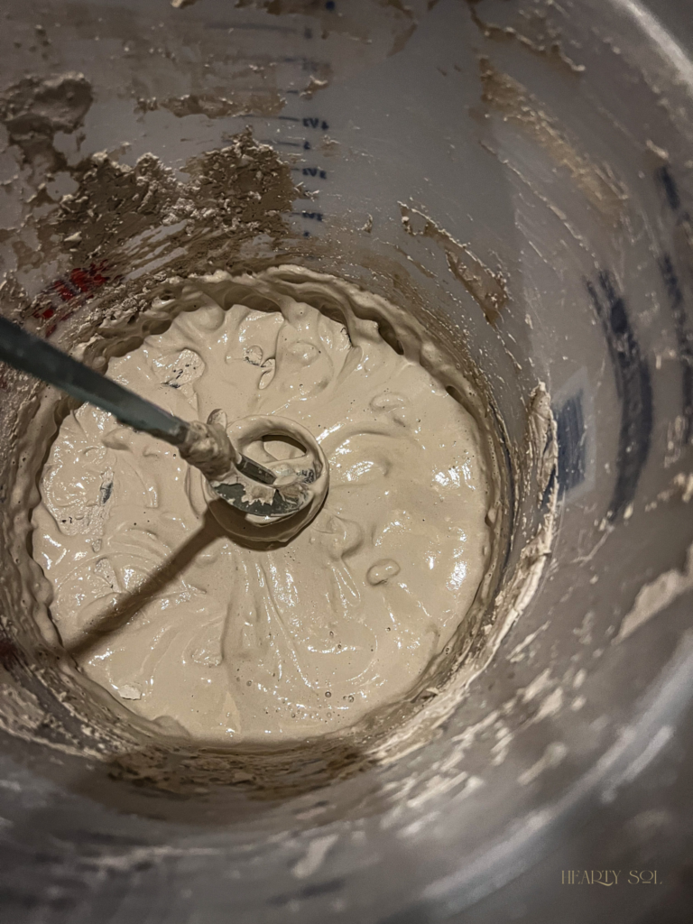 mixing roman clay in a bucket with drill paint mixer