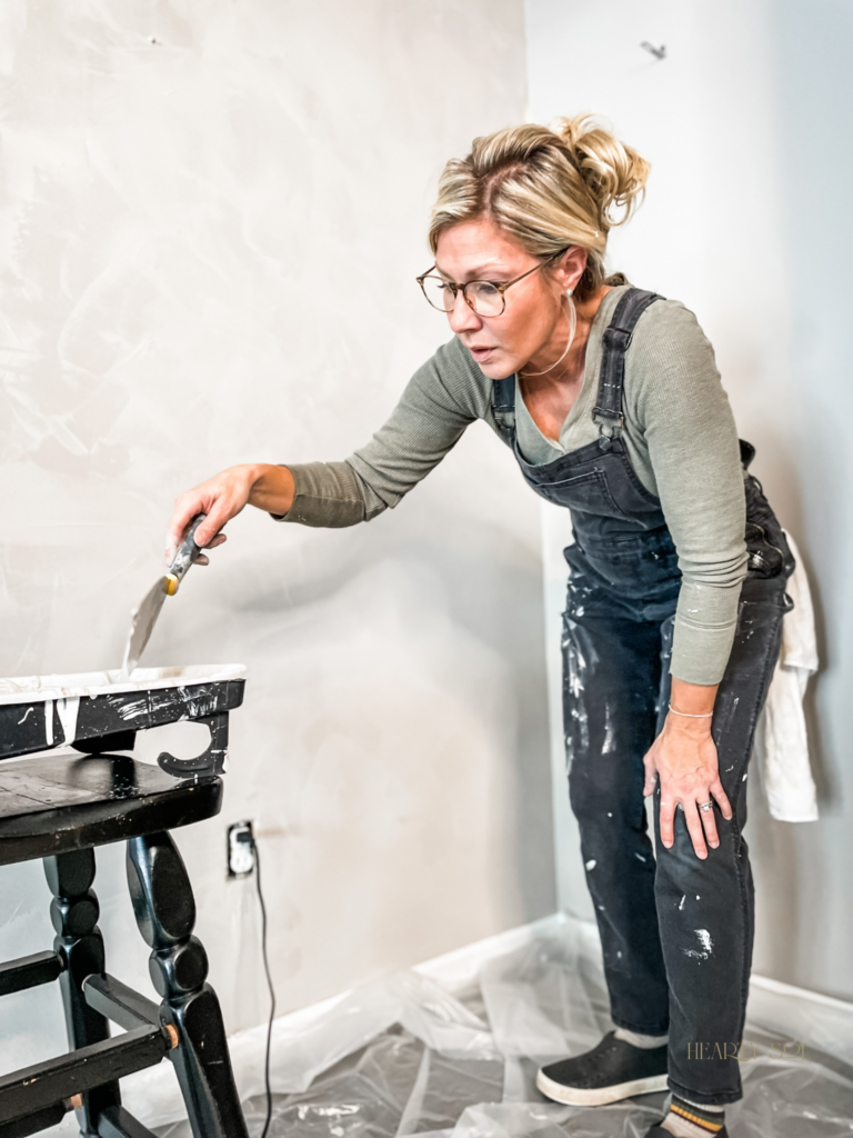 woman dipping paint scrapper into paint pan