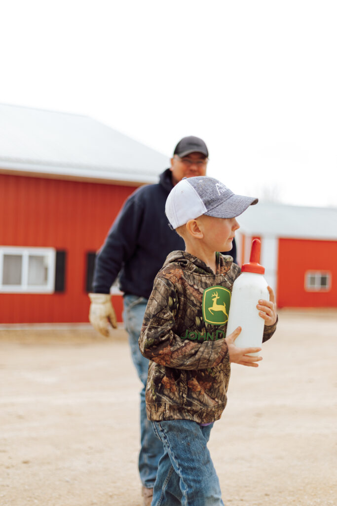 boy holding calf bottle