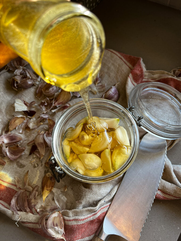 pouring honey onto garlic in a jar