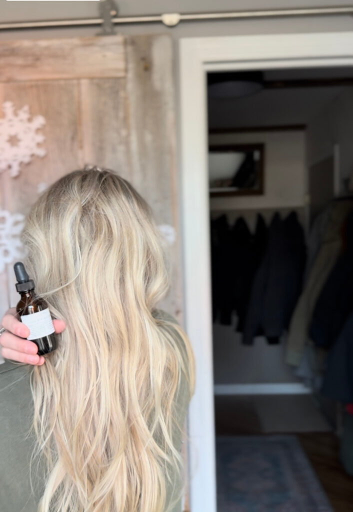 holding hair tonic next to long blond hair